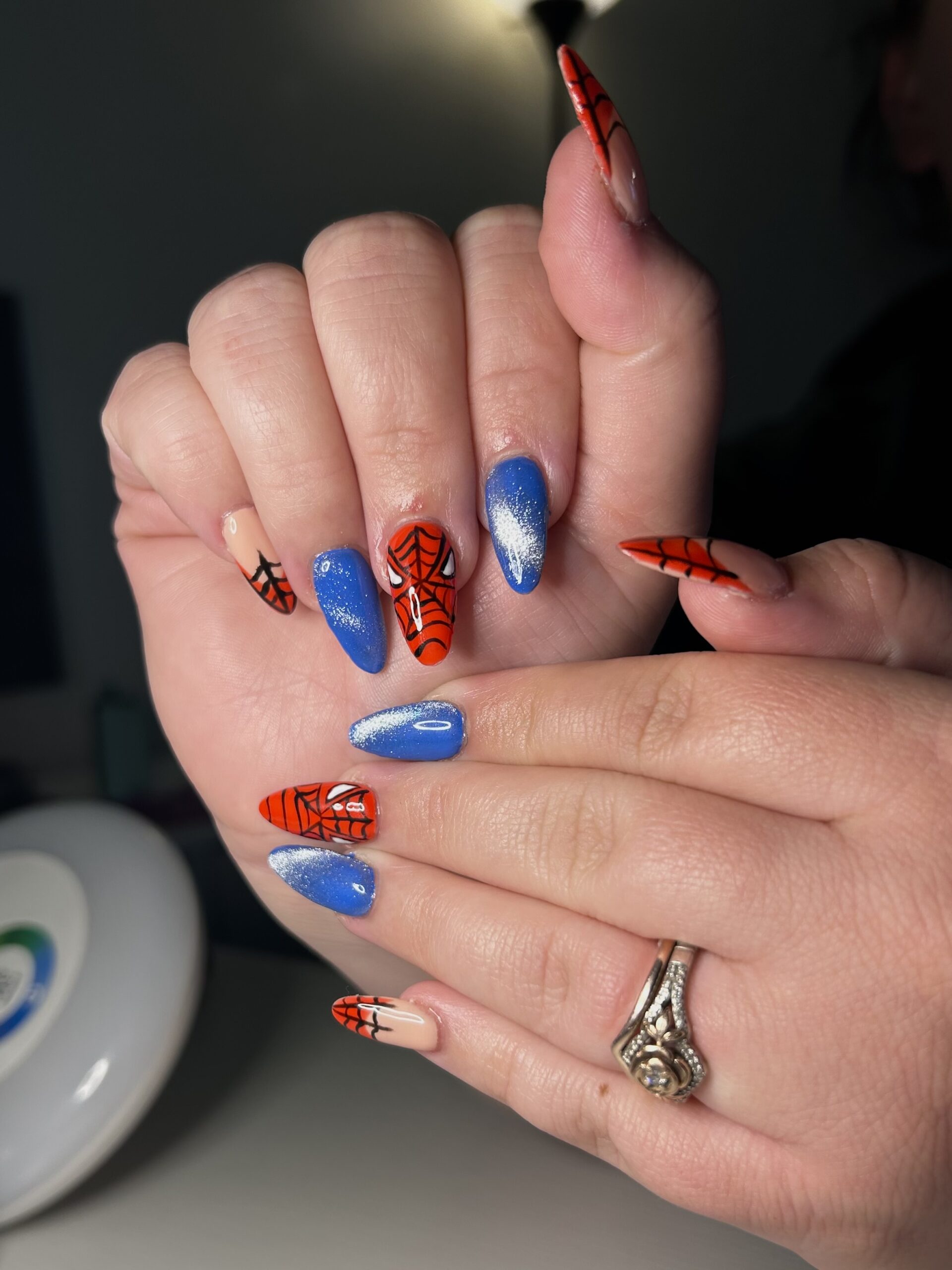 Almond Gel-X nails with blue and red hand-painted spiderweb nail art